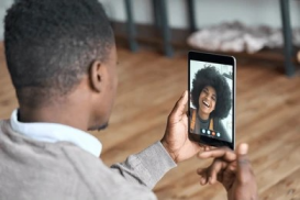 A man on a video call with his girlfriend using an iPad, showing a friendly expression while communicating.