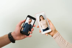 Two people hold their phones displaying a man and woman on the screens, engaged in a video call.