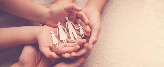 A pair of hands holds a family of paper cutouts, symbolizing unity and creativity in a playful display.