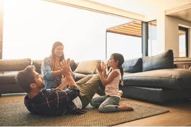  A family enjoying time together on the floor of a living room, with a warm atmosphere and colorful decor.