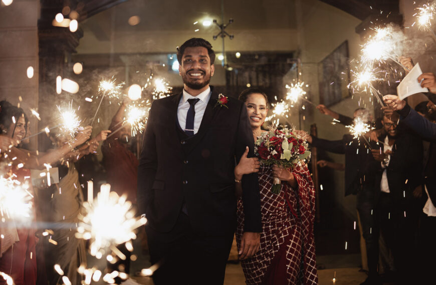 Couple holds hands walking through a sparkler send-off at their wedding, celebrating love and marriage in Sri Lanka, featured on Poruwa.lk | ශ්‍රී ලාංකීය මංගල යෝජනා, Mangala Yojana, Sri Lanka matrimony, and top marriage proposals.