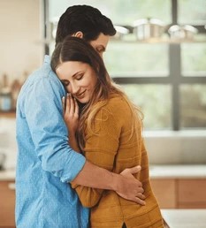 In a bright kitchen, a man and woman share a heartfelt hug, conveying warmth and affection.
