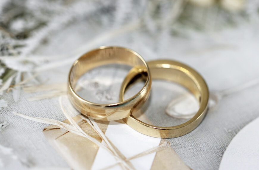 A pair of gold wedding rings elegantly displayed on a wooden table, symbolizing love and commitment.