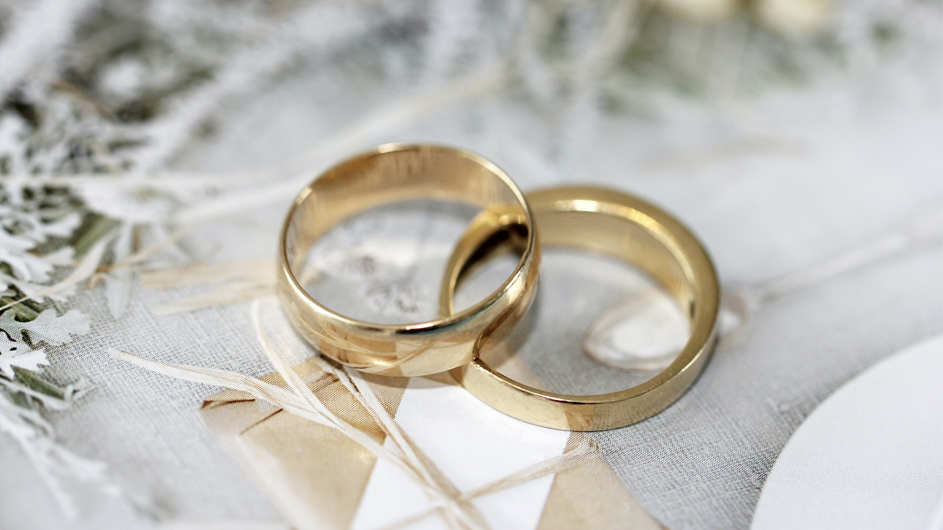A pair of gold wedding rings elegantly displayed on a wooden table, symbolizing love and commitment.