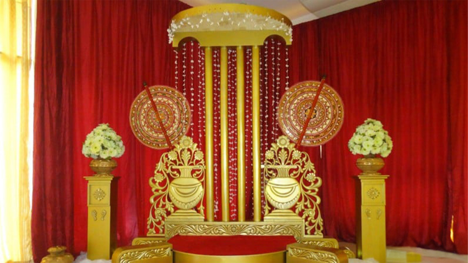 Ornate Sri Lankan wedding ceremonial stage with a gold domed canopy, red curtains, floral arrangements, and intricate patterns, featured on Poruwa.lk | ශ්‍රී ලාංකීය මංගල යෝජනා, Mangala Yojana, Sri Lanka matrimony, and top marriage proposals.