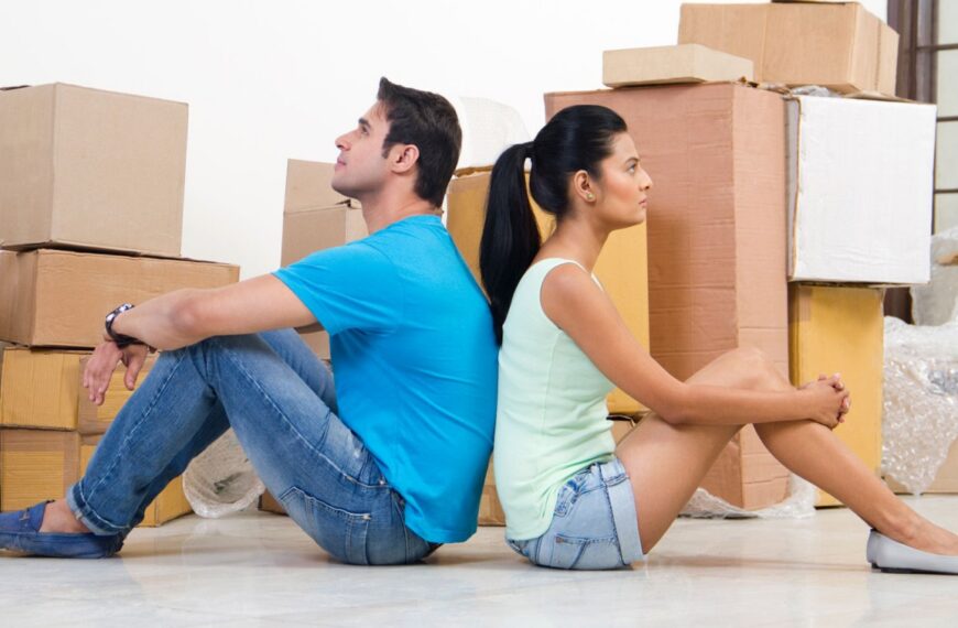 A man and woman sit back-to-back among moving boxes, symbolizing new beginnings while exploring marriage proposals in Sri Lanka through a wedding proposal website, Mangala Yojana, Sri Lankan matrimony, and planning a traditional Poruwa ceremony for Lanka brides and grooms.