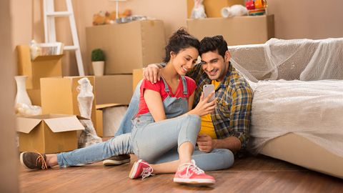 A couple sits on the floor surrounded by unpacked boxes, appearing relaxed and engaged in conversation, symbolizing harmony in SriLanka matrimony and matrimony Sri Lanka, exploring marriage proposals Sri Lanka, and preparing for a joyful Poruwa ceremony.
