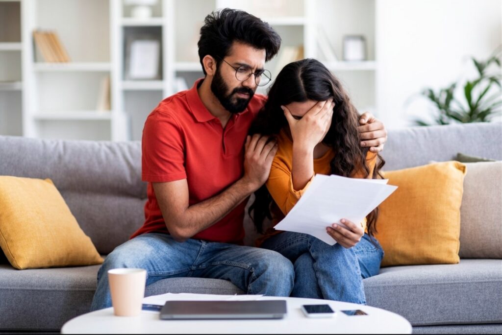 A Sri Lankan couple sitting on a couch reviewing documents together, discussing important life decisions and building a future after marriage proposals Sri Lanka. Represents relationship planning, mangala yojana, and meaningful connections through Poruwa.lk | ශ්‍රී ලාංකීය මංගල යෝජනා, a trusted wedding proposal website for matrimony Sri Lanka, srilanka matrimony, lanka brides and grooms, buddhist matrimony, catholic marriage proposals, and liyathabara marriage proposals in Sri Lanka.