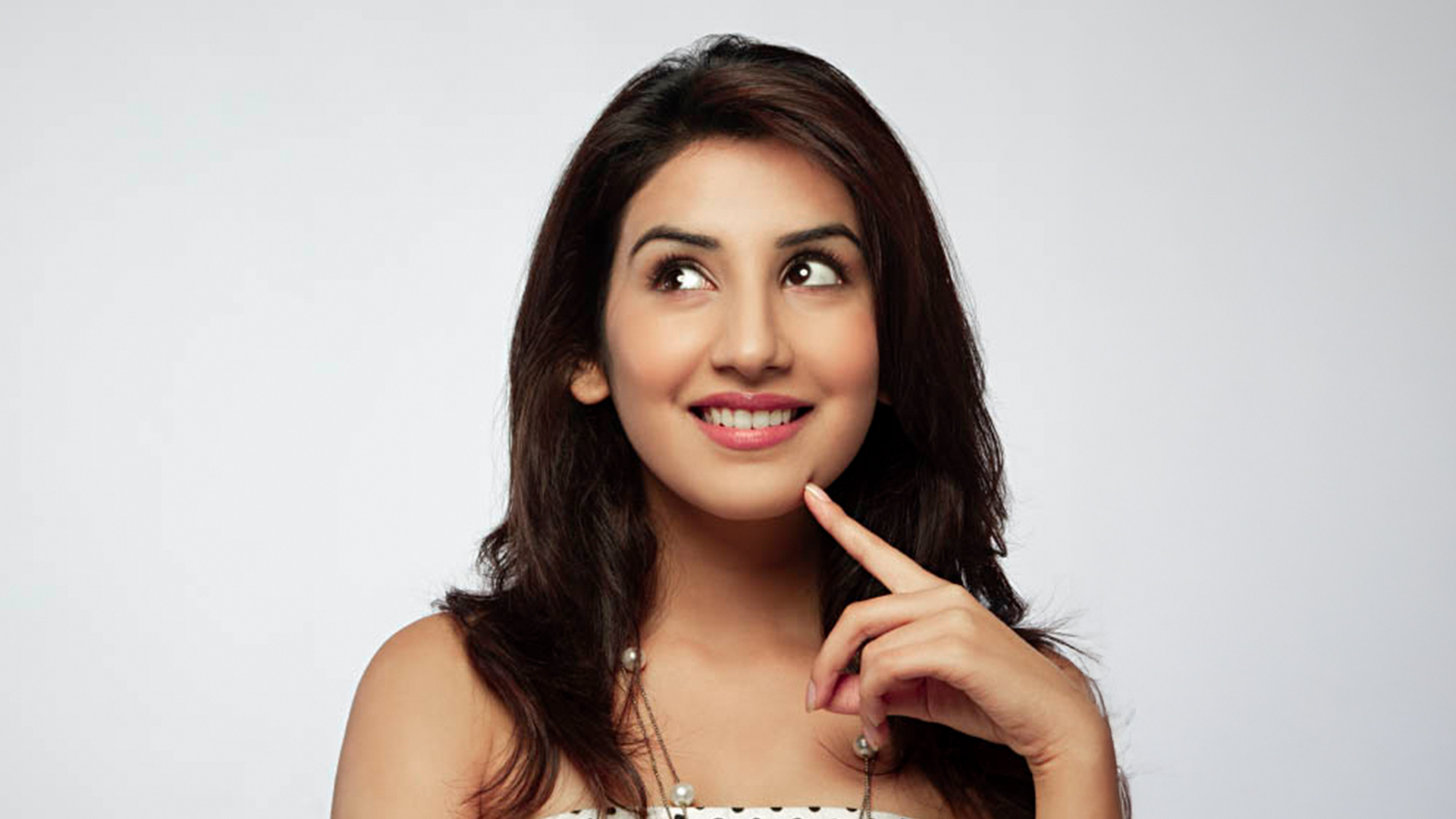 A smiling woman resting her chin on her hand, exuding a thoughtful and cheerful demeanor, representing the joyful spirit of SriLanka matrimony and matrimony Sri Lanka, while symbolizing love, marriage proposals Sri Lanka, and the cultural beauty of a Poruwa ceremony.