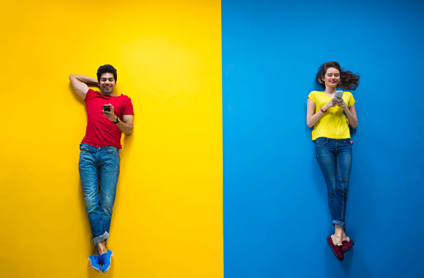 Two individuals wearing contrasting colors hold smartphones, engaged in conversation or sharing information, highlighting connection and digital communication.