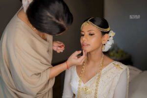 A woman receiving makeup application from a professional bridal makeup artist in a bright studio, reflecting the elegance of Sri Lanka matrimony, Poruwa.lk | ශ්‍රී ලාංකීය මංගල යෝජනා, mangala yojana traditions, and the beauty seen in marriage proposals Sri Lanka and lanka brides and grooms.