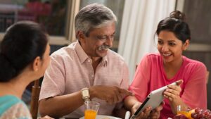 A young South Asian couple discussing marriage proposals in Sri Lanka with an older man using a tablet, exploring options on Poruwa.lk, a trusted Sri Lankan matrimonial website.