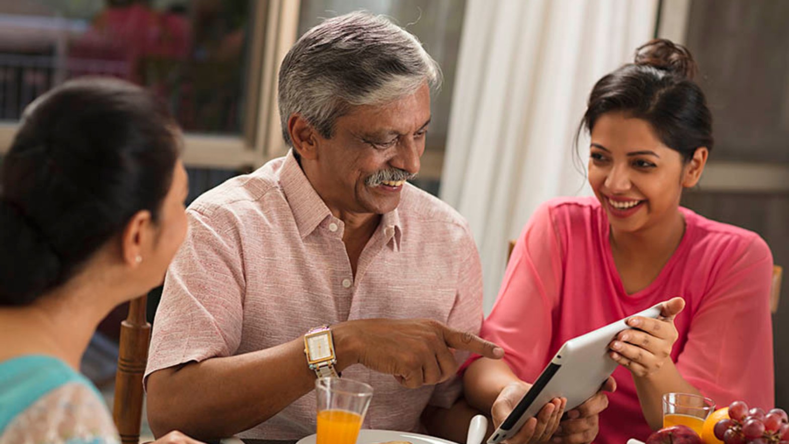 A young South Asian couple discussing marriage proposals in Sri Lanka with an older man using a tablet, exploring options on Poruwa.lk, a trusted Sri Lankan matrimonial website.
