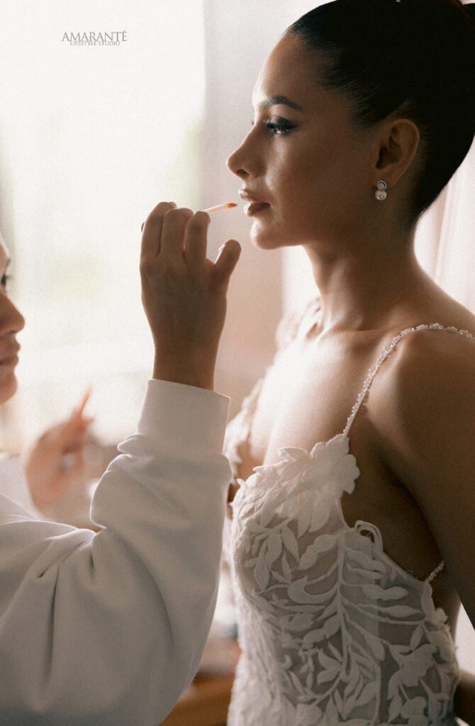 Bride receiving final makeup touches while wearing an elegant lace wedding dress, as a makeup artist applies lip color in a serene and intimate setting, representing Sri Lankan matrimony, matrimony Sri Lanka, marriage proposal Sri Lanka, marriage proposals in Sri Lanka, marriage proposals Sri Lanka, mangala yojana, wedding proposal website services, traditional bridal beauty, and modern wedding preparations through Poruwa.lk | ශ්රී ලාංකීය මංගල යෝජනා.