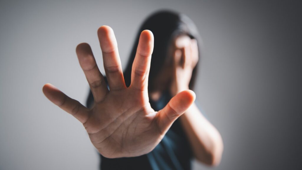Woman with long hair covering her face and holding a hand in a stop gesture, representing hidden violence against women in Sri Lanka during marriage proposals, mangala yojana, poruwa.lk | ශ්රී ලාංකීය මංගල යෝජනා, poruwa ceremony, and matrimony traditions.