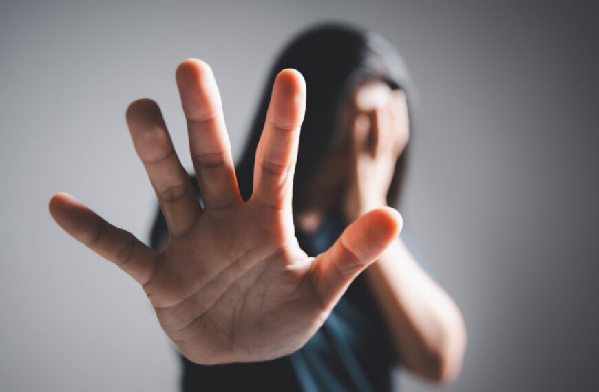 Woman with long hair covering her face and holding a hand in a stop gesture, representing hidden violence against women in Sri Lanka during marriage proposals, mangala yojana, poruwa.lk | ශ්‍රී ලාංකීය මංගල යෝජනා, poruwa ceremony, and matrimony traditions.