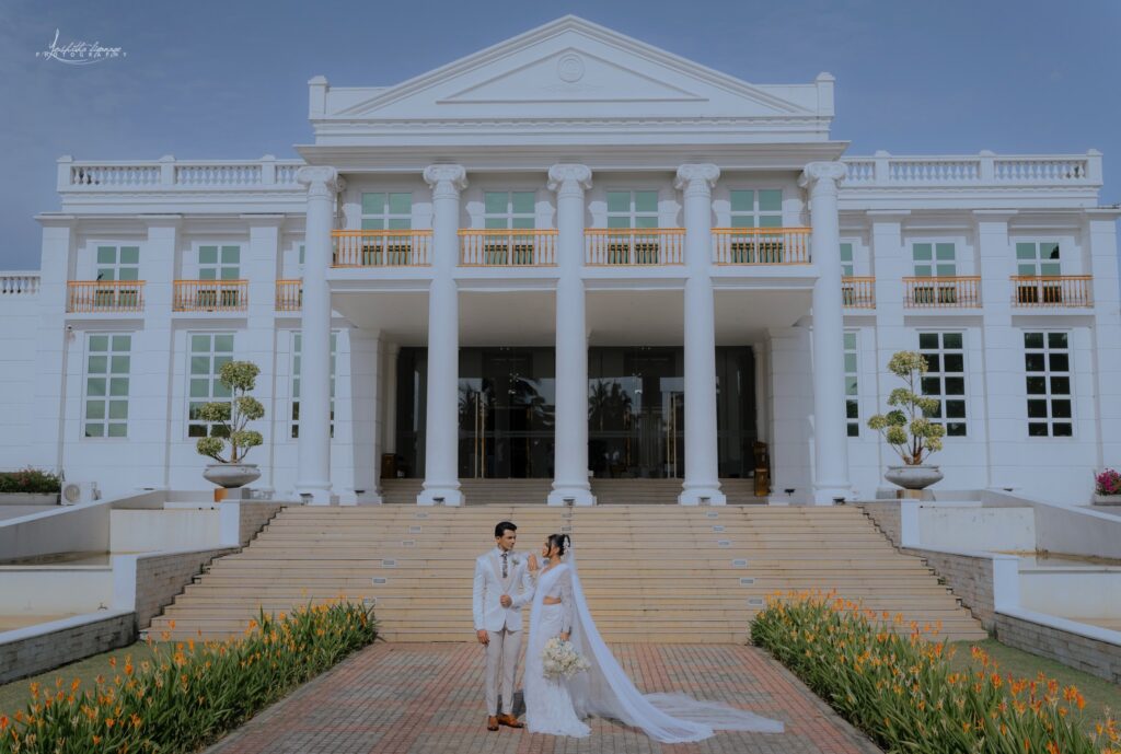 Bride and groom in elegant wedding attire standing in front of a luxury venue, perfect for matrimony Sri Lanka weddings, Poruwa ceremony celebrations, and marriage proposals in Sri Lanka for lanka brides and grooms.