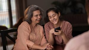 A young woman and her mother discussing marriage proposals in Sri Lanka while browsing a wedding proposal website on a mobile phone together.