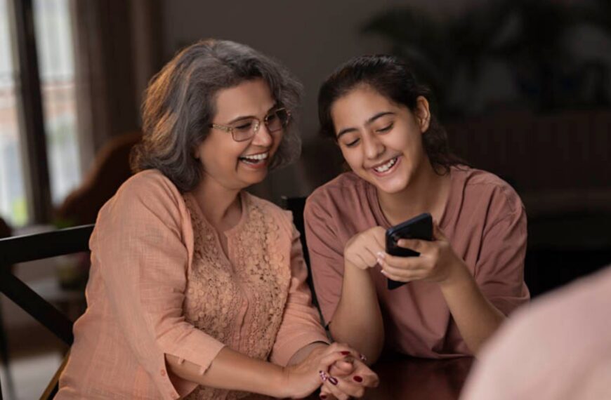 A young woman and her mother discussing marriage proposals in Sri Lanka while browsing a wedding proposal website on a mobile phone together.
