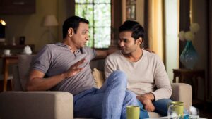 Two Sri Lankan men engaged in a thoughtful conversation while sitting on a couch in a cozy living room, discussing marriage proposals and family matters.