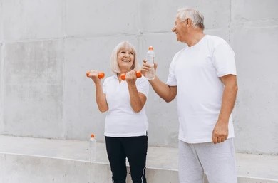 An older couple lifting dumbbells together, demonstrating fitness and strength in a bright, home exercise setting.