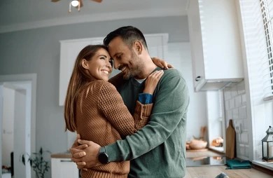 A couple shares a loving embrace in their kitchen, creating a warm and inviting atmosphere in their home.
