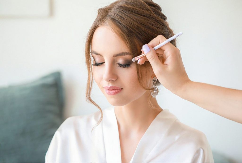 Professional bridal makeup artist applying makeup to a woman during a beauty session, highlighting elegant bridal preparation for a Sri Lankan wedding ceremony.