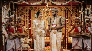 A joyful modern couple holds hands during a traditional Sri Lankan wedding ceremony in a natural outdoor garden setting. The bride wears a stunning white Osariya, and the groom is in Nilame attire, surrounded by traditional Kandyan drummers for a beautiful Poruwa ceremony.