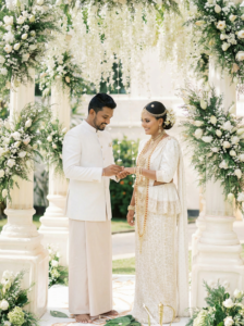 A photographer capturing a Kerala wedding ceremony featuring a bride and groom in traditional attire, surrounded by vibrant floral decorations, cultural rituals, and a beautifully arranged wedding setting.