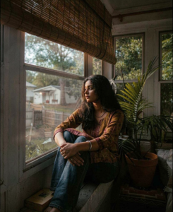 A Sri Lankan woman sitting thoughtfully on a window sill in soft natural light, reflecting on mangala yojana, marriage proposals in Sri Lanka, Sri Lankan matrimony, and finding a suitable life partner through online marriage proposals.