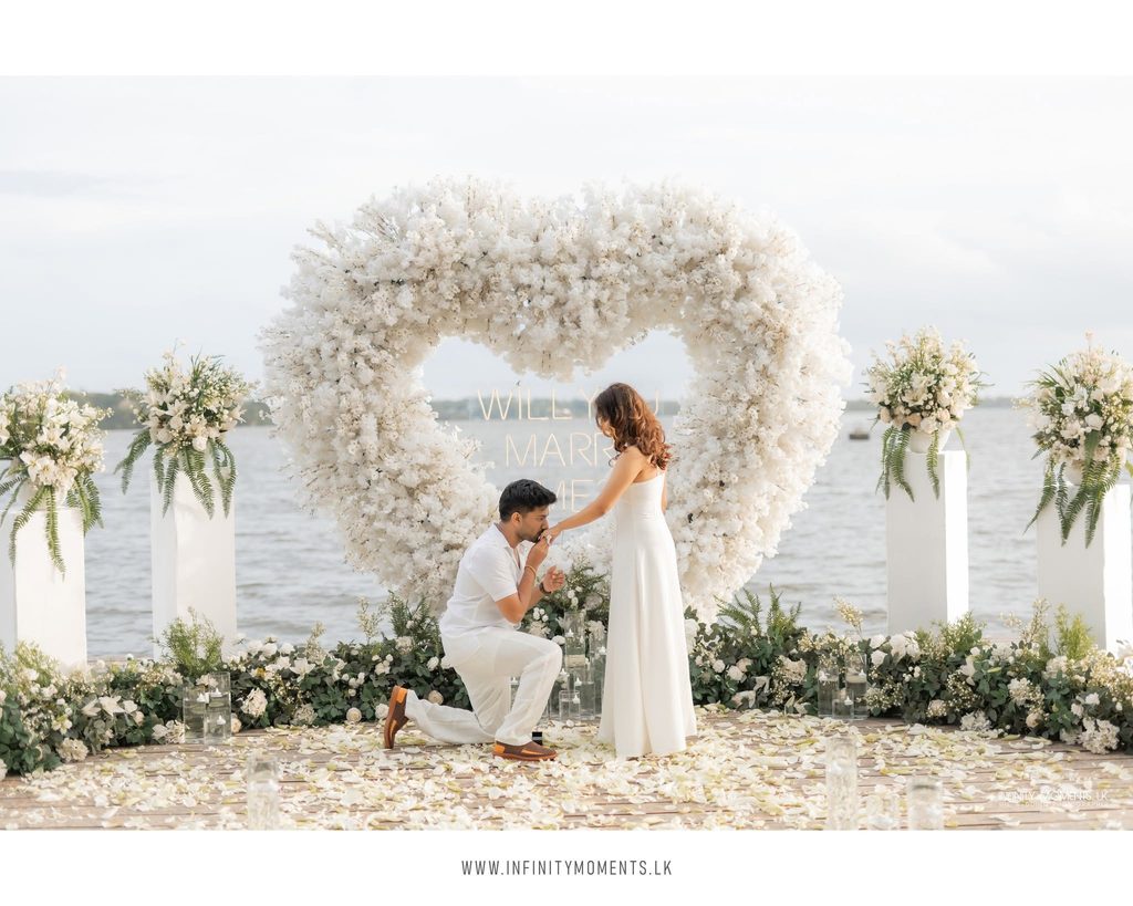 A Sri Lankan wedding ceremony taking place in front of a large heart-shaped floral arrangement, symbolizing love and unity and reflecting mangala yojana traditions, marriage proposals in Sri Lanka, matrimony Sri Lanka, srilanka matrimony, lanka brides and grooms, Buddhist matrimony, Catholic marriage proposals, liyathabara marriage proposals in Sri Lanka, and Poruwa.lk | ශ්‍රී ලාංකීය මංගල යෝජනා.