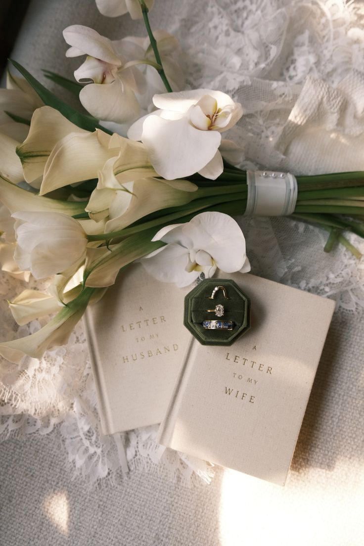 Wedding rings resting on a book surrounded by delicate white flowers, symbolizing love and commitment, with inspiration for Sri Lankan wedding traditions, wedding poruwa, wedding nakath, and wedding planning in Sri Lanka.